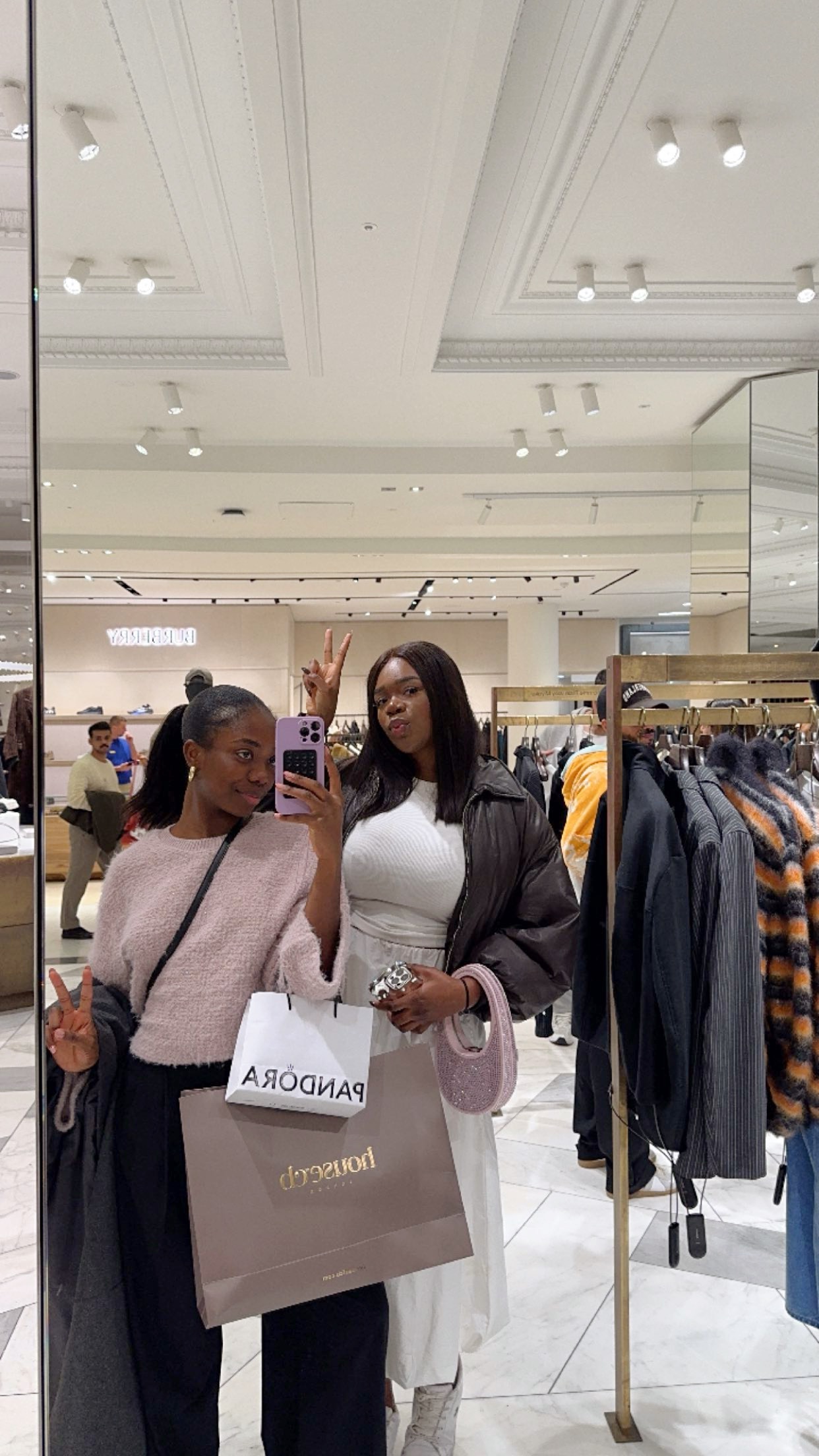 Tumininu and Fareedah taking a mirror selfie while shopping in a department store.